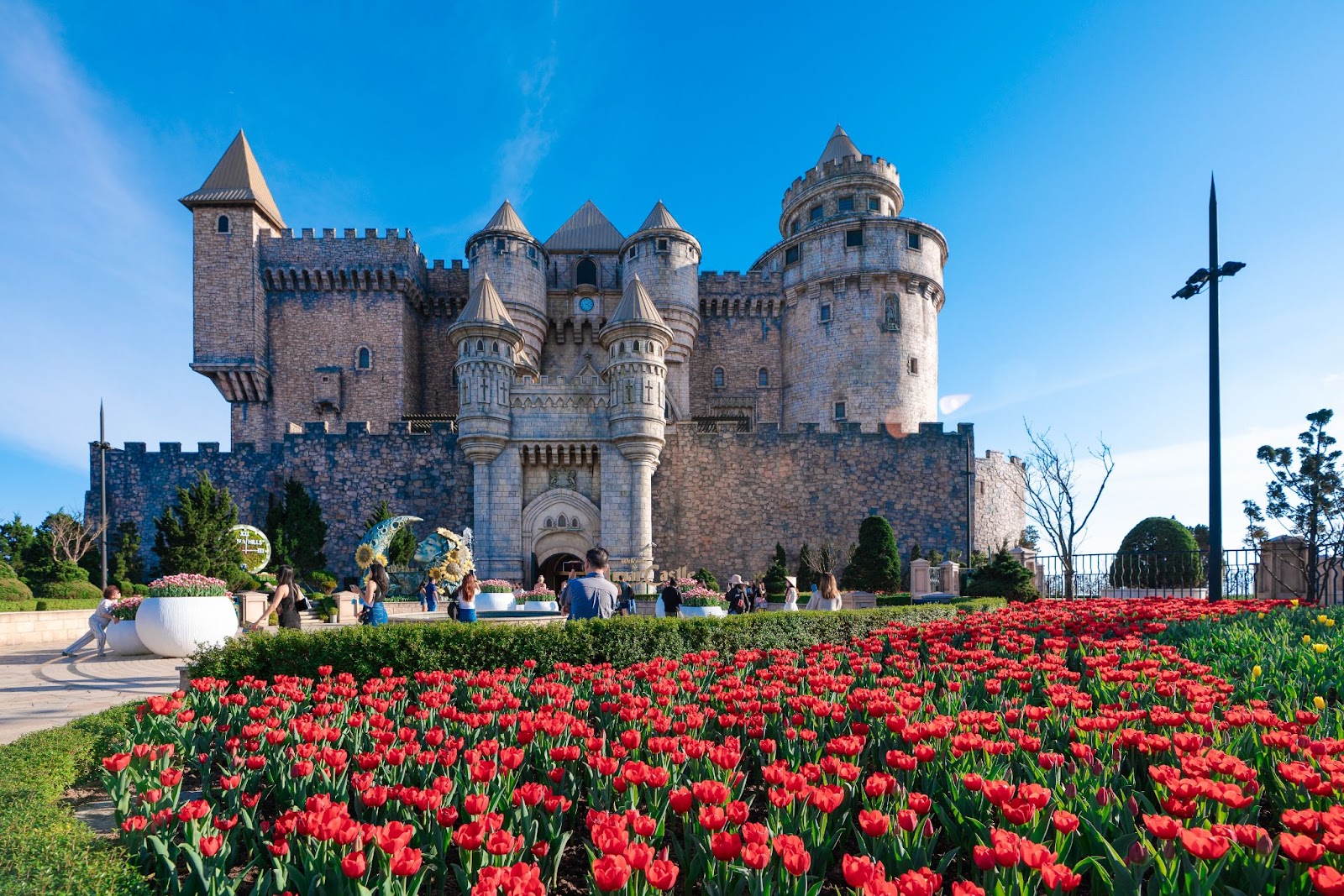 The majestic Gothic-style architecture at Sun World Ba Na Hills, beside a blooming tulip garden
