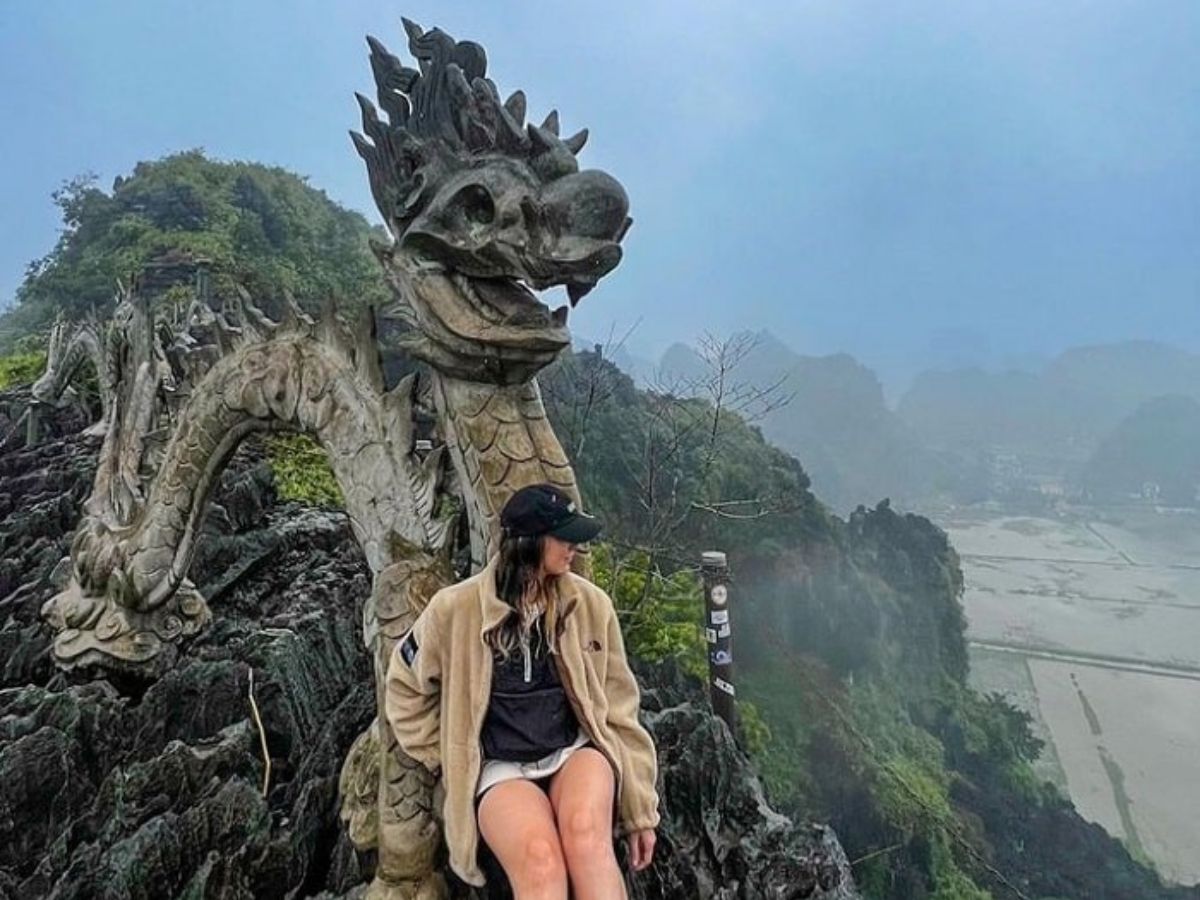 Du khách check-in bên tượng rồng đá trên đỉnh Ngọa Long, thu trọn vẻ đẹp núi non Ninh Bình phía sau. (Nguồn: Sưu tầm)