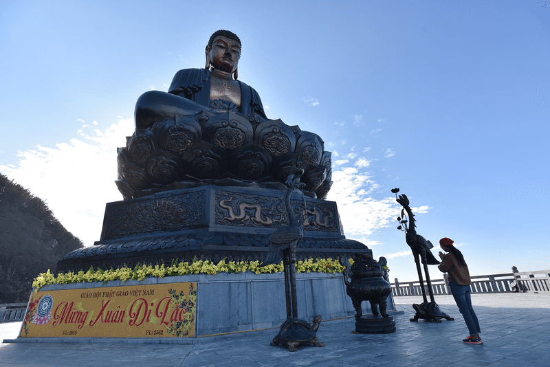 Tourists pray before the Great Buddha statue on the summit of Fansipan