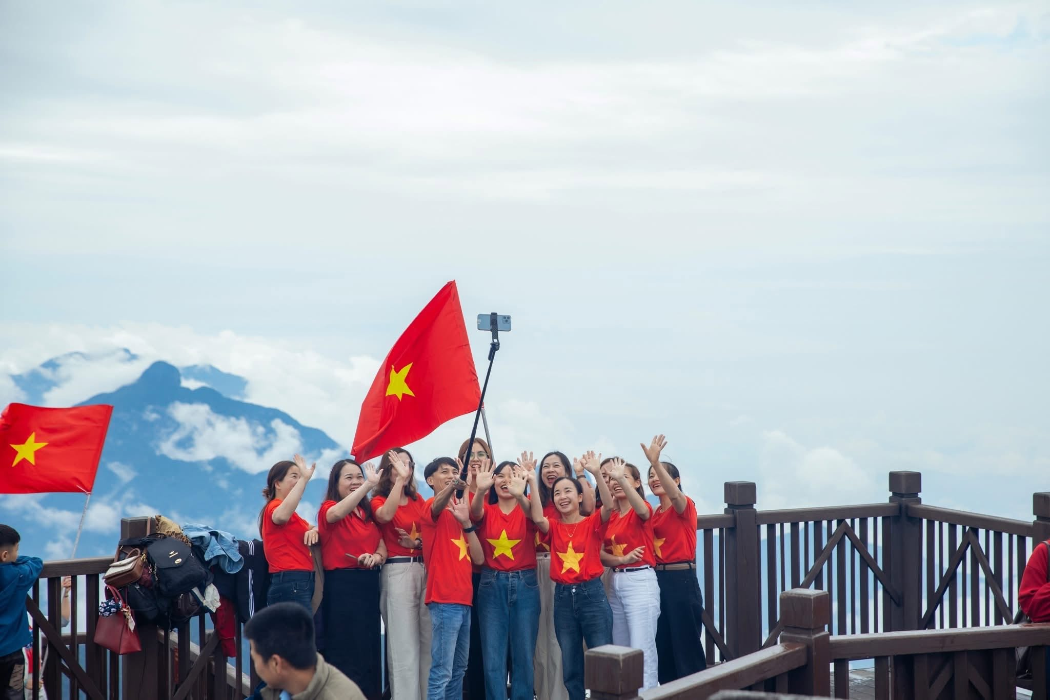 Nhóm du khách rạng rỡ mặc áo cờ đỏ sao vàng check-in trên đỉnh Fansipan