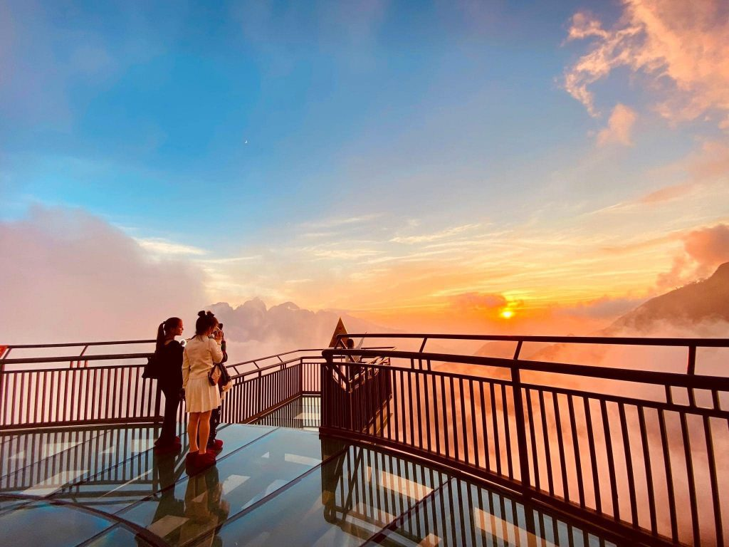 Tourists watch the sunset from the glass bridge