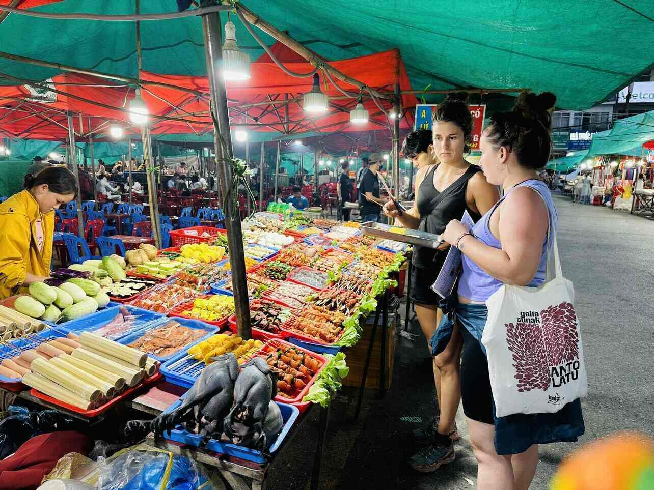 Tourists enjoy grilled meat skewers at Sapa night market