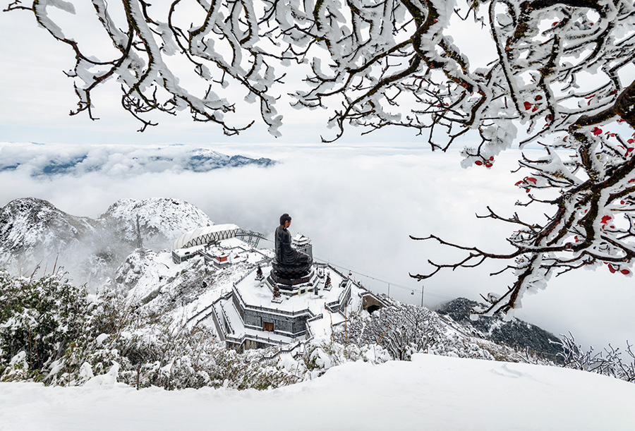 The landscape is covered in white snow on the summit of Fansipan