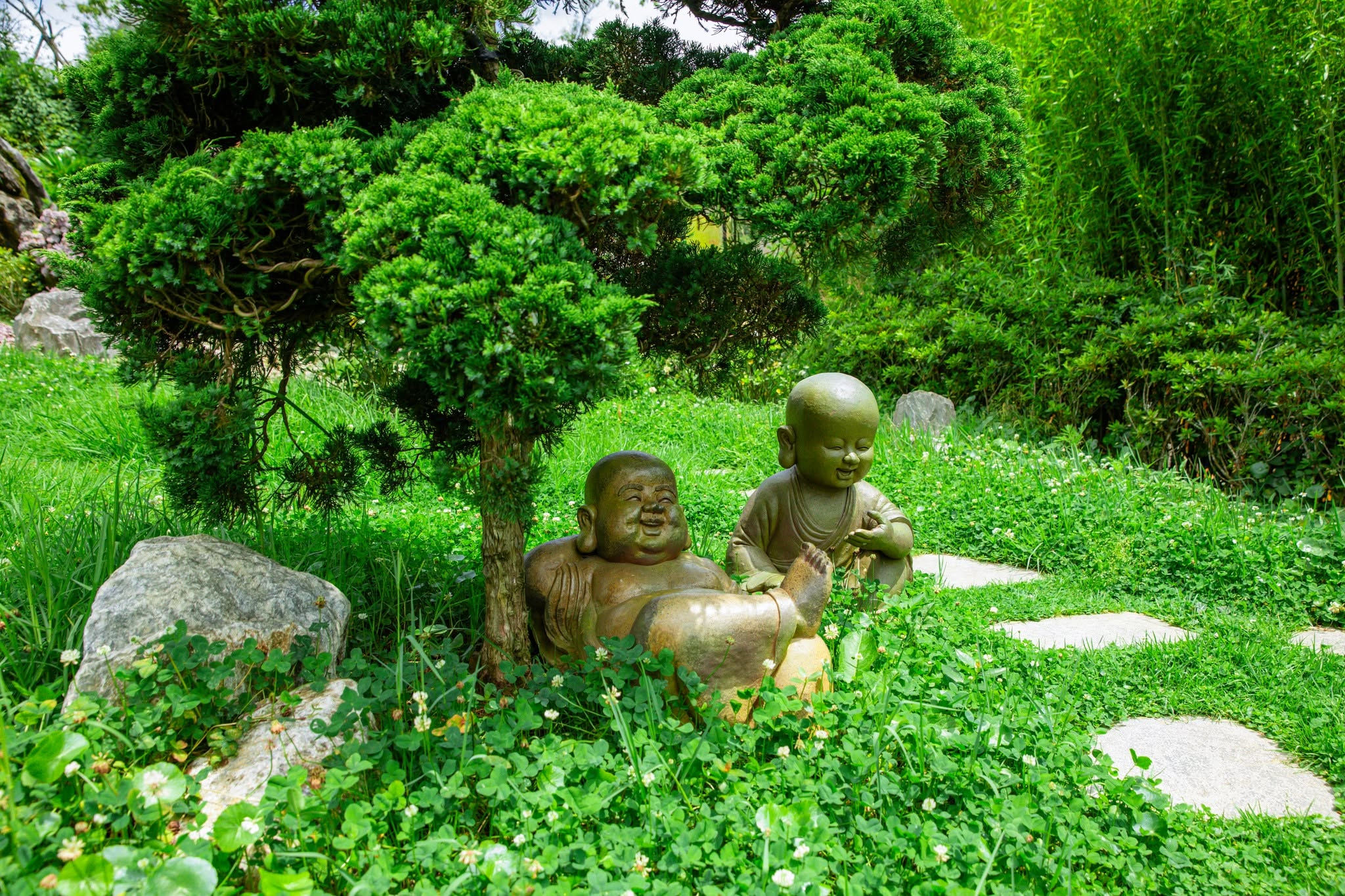 Tượng chú tiểu ngây thơ được đặt xen kẽ giữa thảm cây xanh mang tới cảm giác an lạc. (Nguồn: Sưu tầm)