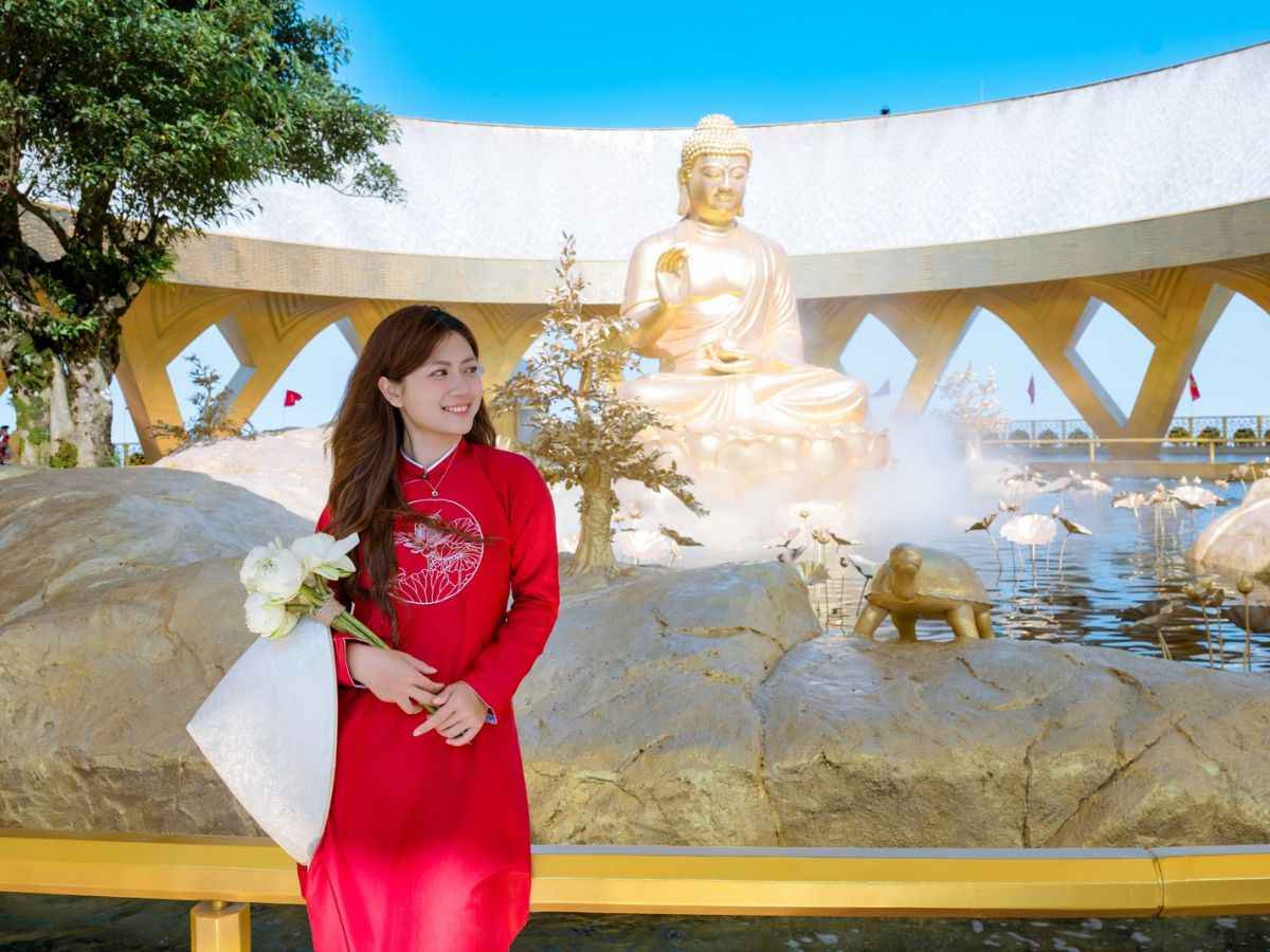 Du khách chụp ảnh bên tượng Phật Câu Na Hàm Mâu Ni trên đỉnh núi.