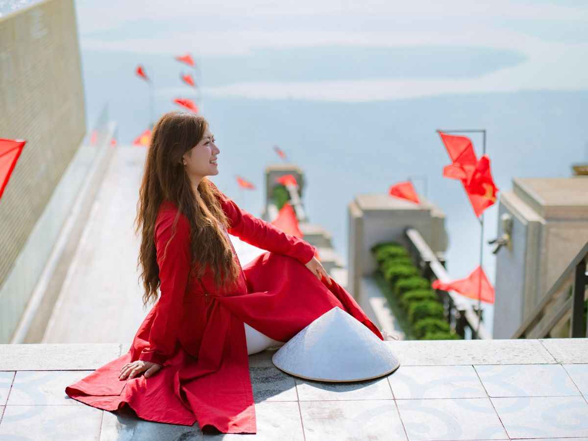 Du khách check-in trên đỉnh Núi Bà Đen với nền trời và cờ đỏ.