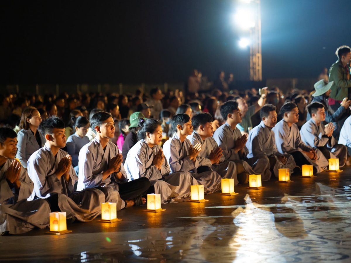 Phật tử ngồi tĩnh tâm bên ánh đăng trong không gian hành hương đêm.