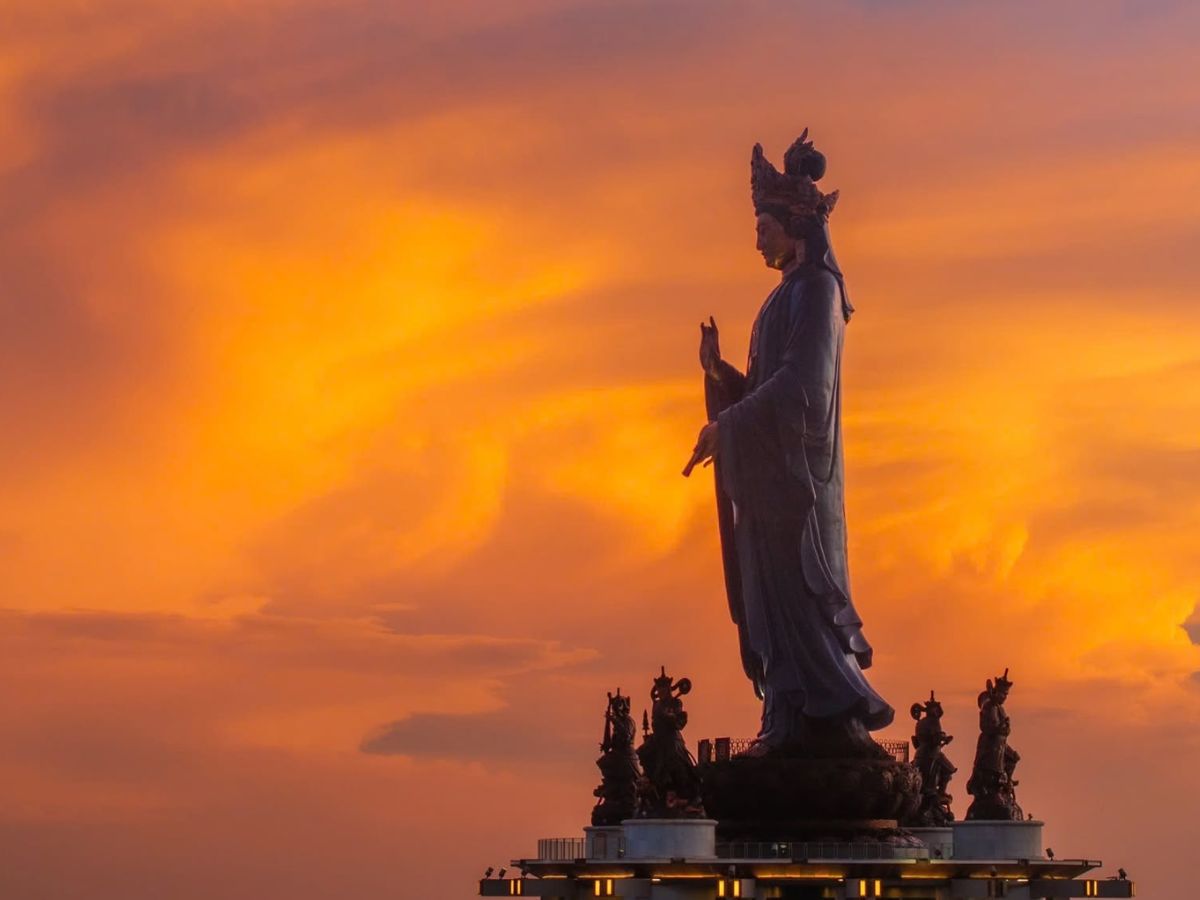 Tượng Phật Bà Tây Bổ Đà Sơn giữa hoàng hôn trên đỉnh núi.