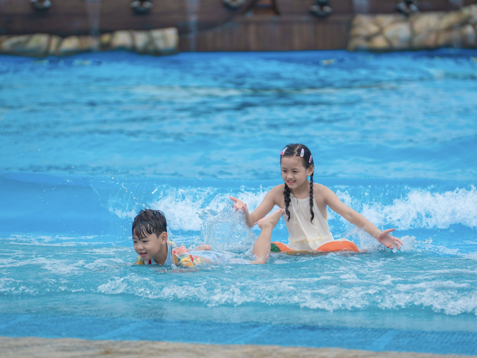 Hai em nhỏ vui đùa tại hồ tạo sóng Sun World Vung Tau, tận hưởng làn nước mát và những khoảnh khắc vui tươi đầy năng lượng.