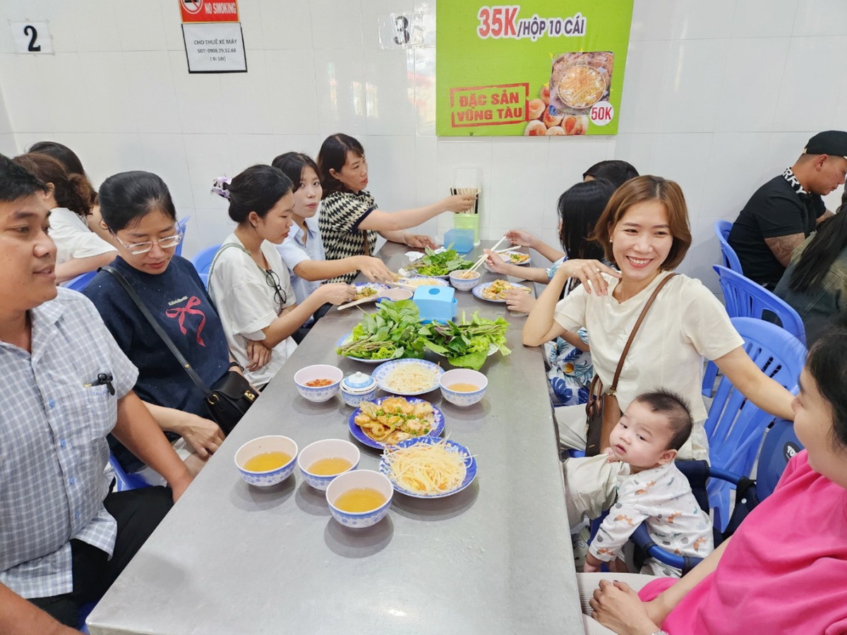 Du khách thưởng thức bánh khọt Vũng Tàu giòn rụm, nóng hổi, kết hợp rau sống tươi và nước mắm chua ngọt.